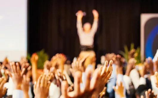 sala pełna ludzi z podniesionymi rękami